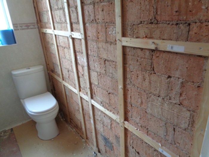 Unfinished bathroom with exposed brick walls